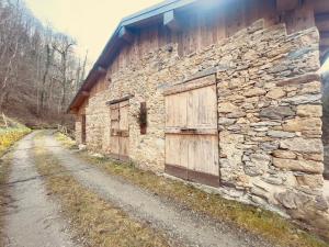 a stone building with wooden doors and a road at Al Foér Guesthouse in Averara
