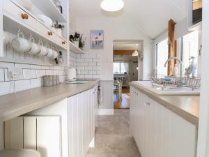 a kitchen with white cabinets and a counter top at Herbies Cottage in Snettisham
