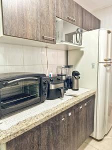 a kitchen with a toaster oven and a refrigerator at Apê Família | Varanda c/ churrasqueira | Garagem in Ponta Grossa +12 photos