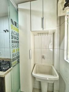 a white bathroom with a sink and a toilet at Apê Família | Varanda c/ churrasqueira | Garagem in Ponta Grossa