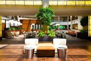 a restaurant with white chairs and tables and plants at Embassy Suites by Hilton Cincinnati Northeast - Blue Ash in Blue Ash
