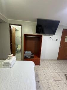a bedroom with a bed and a flat screen tv at Hospedaje W TAWA in Lima