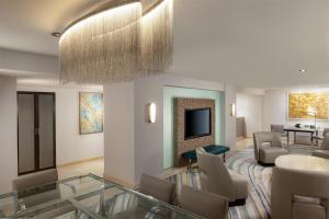 a living room with a couch and chairs and a television at Hilton Los Angeles Airport in Los Angeles