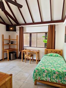 a bedroom with a bed and a table and a desk at Hotel Kaveka in Maharepa