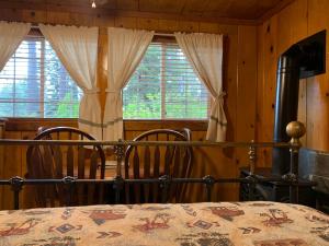 ein Schlafzimmer mit einem Bett, zwei Stühlen und Fenstern in der Unterkunft Rustic Cottages in Tahoe Vista