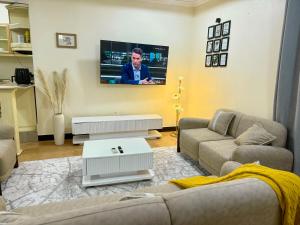 a living room with two couches and a tv on the wall at Jefes Haven in Dar es Salaam