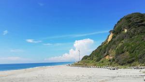 a sandy beach with a hill next to the ocean at stylish japanese beach house in Toyohashi +12 photos