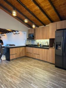 a kitchen with wooden cabinets and a black refrigerator at Nido de Montaña Cabañas in Bello +5 photos
