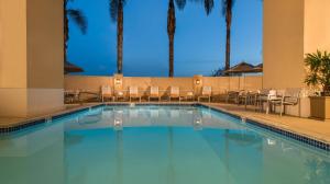 a swimming pool in a hotel with chairs and palm trees at Hilton Santa Clara - Newly Renovated in Santa Clara