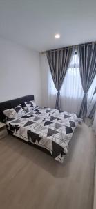 a bed with a black and white comforter in a bedroom at D'Millenia Residences Steady in Kota Samarahan