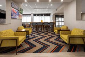 a waiting room with yellow chairs and tables at Hampton Inn Somerset in Somerset