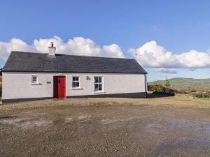 a white house with a red door in a field at Derg Cottage in Strabane