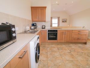 a kitchen with a washing machine and a microwave at Derg Cottage in Strabane