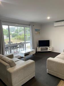 a living room with two couches and a flat screen tv at Bella's Beach House in Venus Bay