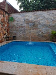 a swimming pool with a waterfall in a brick wall at Cantinho Abençoado in Pirenópolis