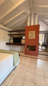 a room with a bed and a brick fireplace at Hotel Pousada Casacolina in Búzios