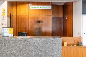 a person is standing in front of a reception desk at HI Lousã – Pousada de Juventude in Lousã