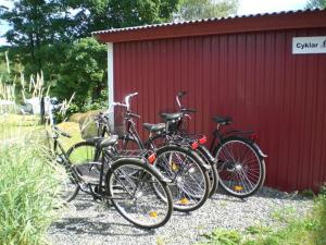 tres bicicletas estacionadas al lado de un edificio rojo en Munkebergs Stugor & Vandrarhem en Filipstad