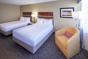 a hotel room with two beds and a chair at Doubletree By Hilton Billings in Billings +48 photos