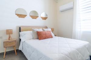 a bedroom with a white bed with a red pillow at Casa Norma in Mayaguez in Hacienda Constanza