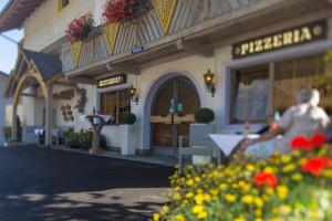 Un uomo seduto davanti a un negozio con dei fiori di Hotel Chalet Olympia a Monguelfo