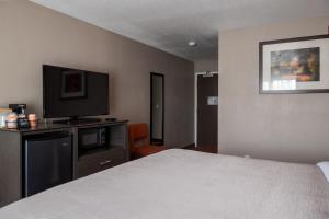 a hotel room with a bed and a flat screen tv at Quality Inn & Suites Fresno Northwest in Fresno