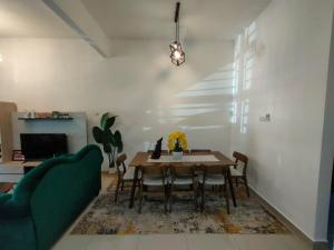 a dining room with a table and a green couch at Seri Jerantut Homestay in Jerantut