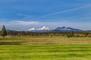 a green field with snow capped mountains in the background at Lodge Room 005 in Black Butte Ranch