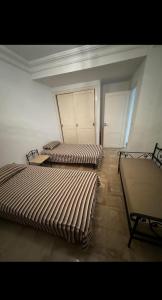 a room with two beds and a chair in it at Appartement rez de jardin in Hammamet