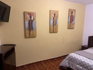 three paintings on a wall in a bedroom at Sandy's in Morelia