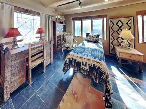 a bedroom with a bed and a desk and windows at Casita Mariposa in Santa Fe