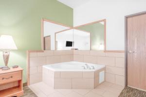 Baymont by Wyndham Pearsall في Pearsall: حمام مع حوض ومرآة كبيرة