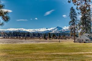 a field with a house and mountains in the background at Lodge Room 018 in Black Butte Ranch