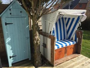 a shed and a chair next to a tree at Kleine Auszeit in Garding