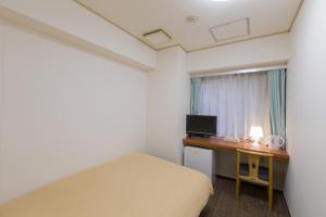 a bedroom with a bed and a desk with a television at Ikebukuro Royal Hotel in Tokyo