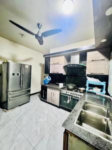 a kitchen with stainless steel appliances and a ceiling fan at Waves Guest House Clifton Khi in Karachi