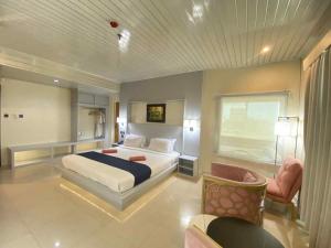 a bedroom with a king sized bed and a chair at Pagadian Bay Plaza Hotel in Pagadian
