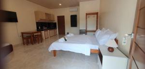 a bedroom with a white bed and a kitchen at Secret Garden Inn in Tagum