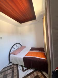 a small bed in a room with a wooden ceiling at JO's HOMEtel SL 1 in Sampong