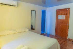 a bedroom with a white bed and a wooden door at Paraiso Playa in Cartagena de Indias