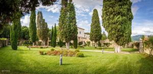 einen Garten mit Bäumen und ein Haus im Hintergrund in der Unterkunft San Pietro Sopra Le Acque Resort & Spa in Massa Martana