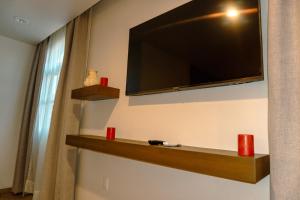 a television hanging on a wall with two red candles at Hotel Tres Reinas in Xicotepec de Juárez