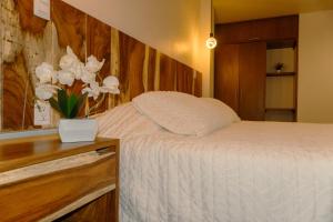 a bedroom with a bed and a vase of white flowers at Hotel Tres Reinas in Xicotepec de Juárez