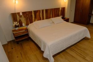 a bedroom with a large bed with a wooden headboard at Hotel Tres Reinas in Xicotepec de Juárez