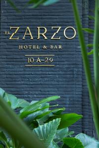 a sign for a hotel and bar with green plants at Hotel El Zarzo in Medellín