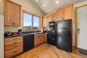 a kitchen with a black refrigerator and wooden cabinets at Teepee Mountain 12A Condo in Estes Park