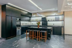a kitchen with black cabinets and a counter with stools at Atlas Serenity Villa Marrakech in Sbiti