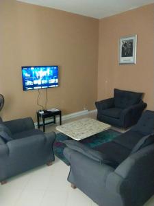 a living room with two couches and a flat screen tv at Keur Fall Aéroport in Saint-Louis
