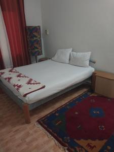 a bed in a room with a white mattress and a rug at Keur Fall Aéroport in Saint-Louis
