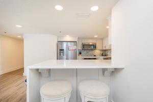a kitchen with a white counter and two stools at Phoenix VI 6906 in Orange Beach